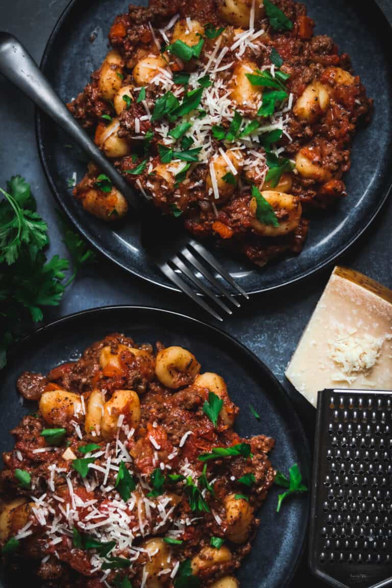 Gnocchi Bolognese with parsley and Parmesan cheese on top.