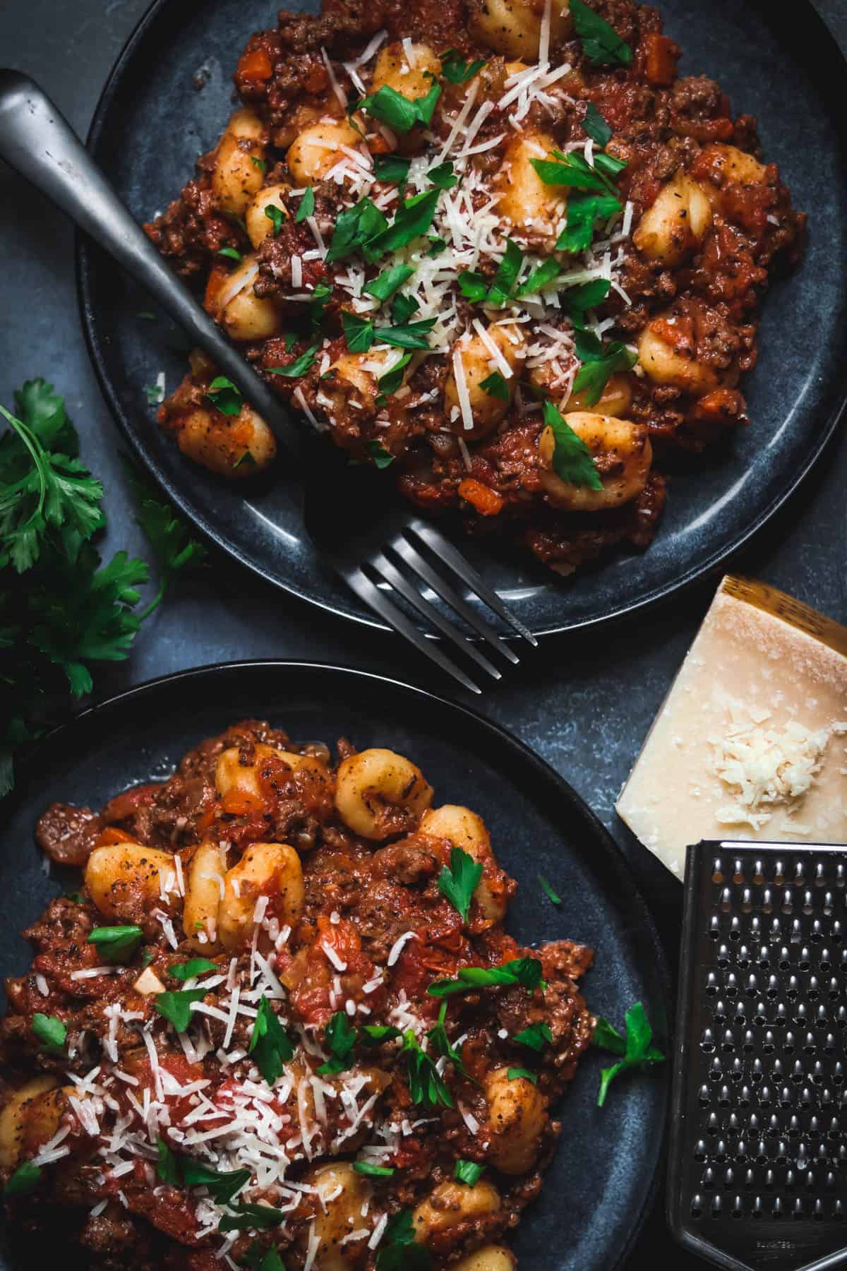 Gnocchi Bolognese with parsley and Parmesan cheese on top.