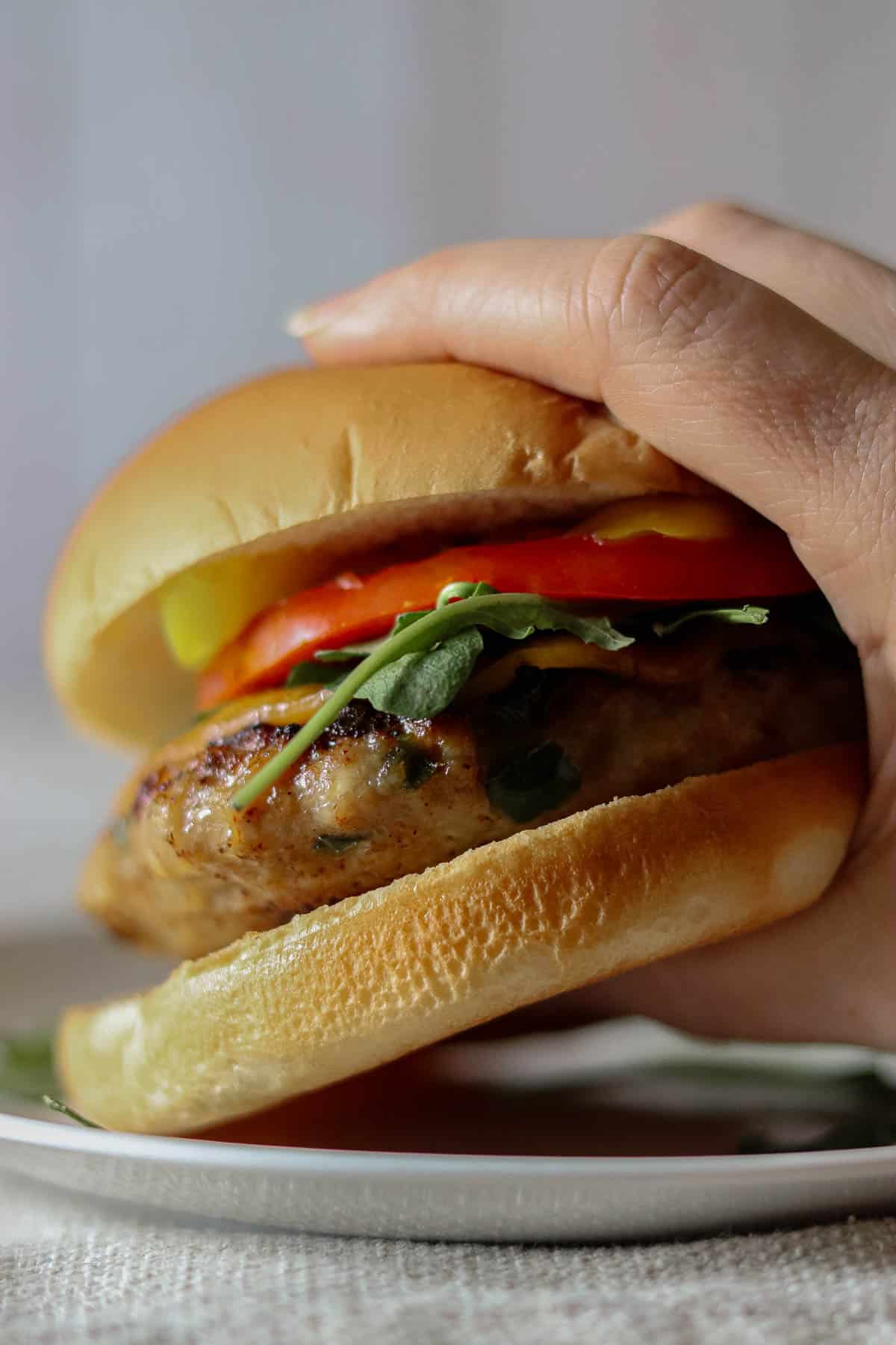Hand picking a burger up off the plate.