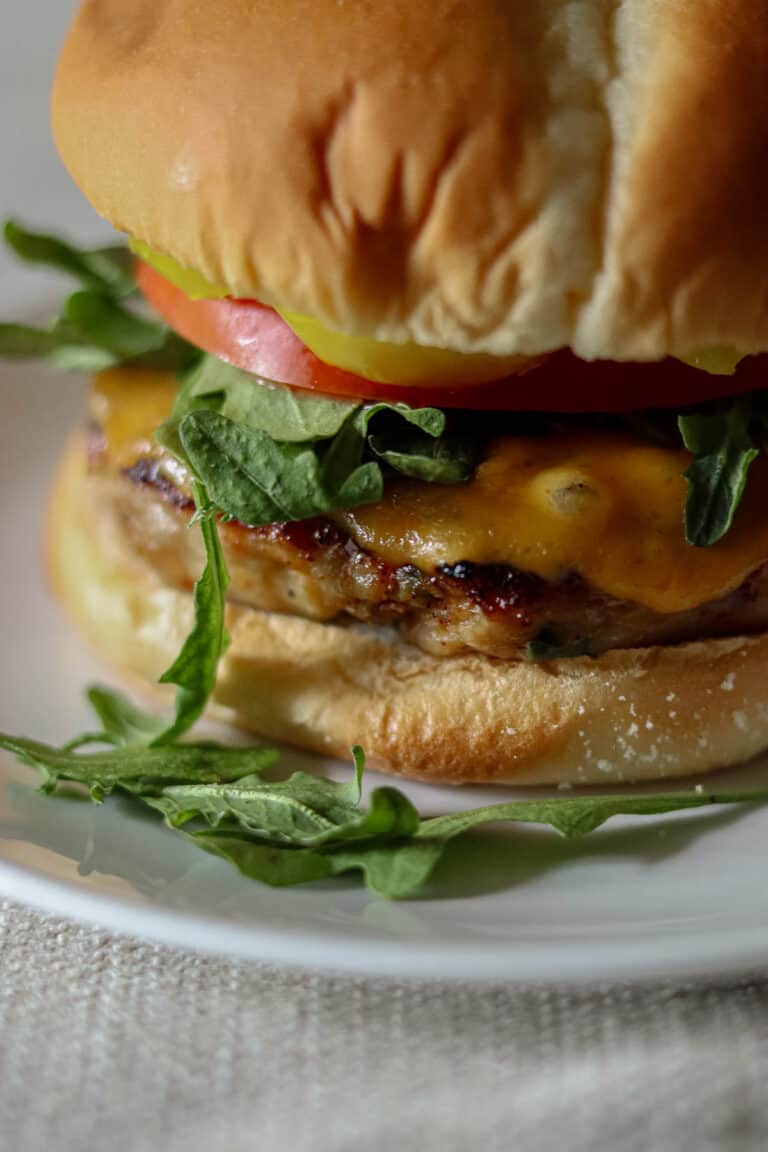 Chicken burger on a white plate with arugula.