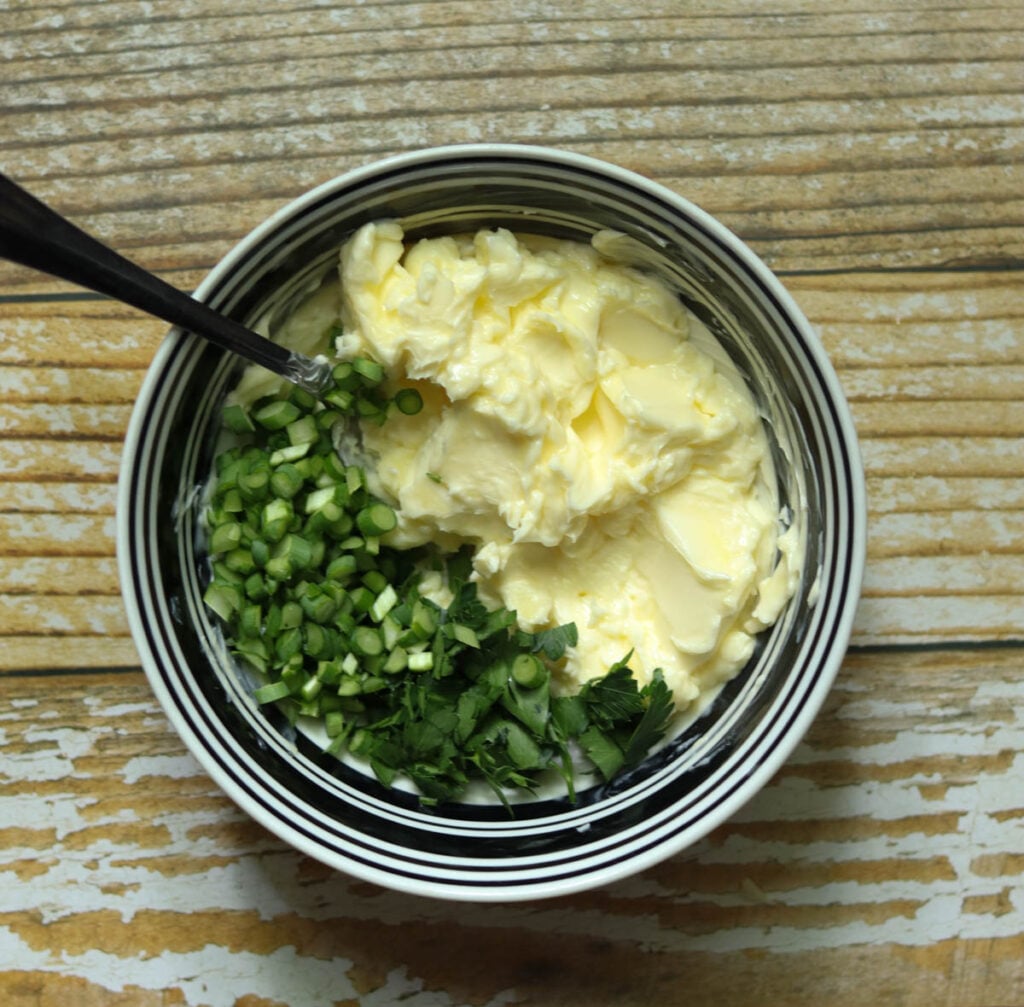 Butter, parsley, and chopped garlic scapes in a bowl.