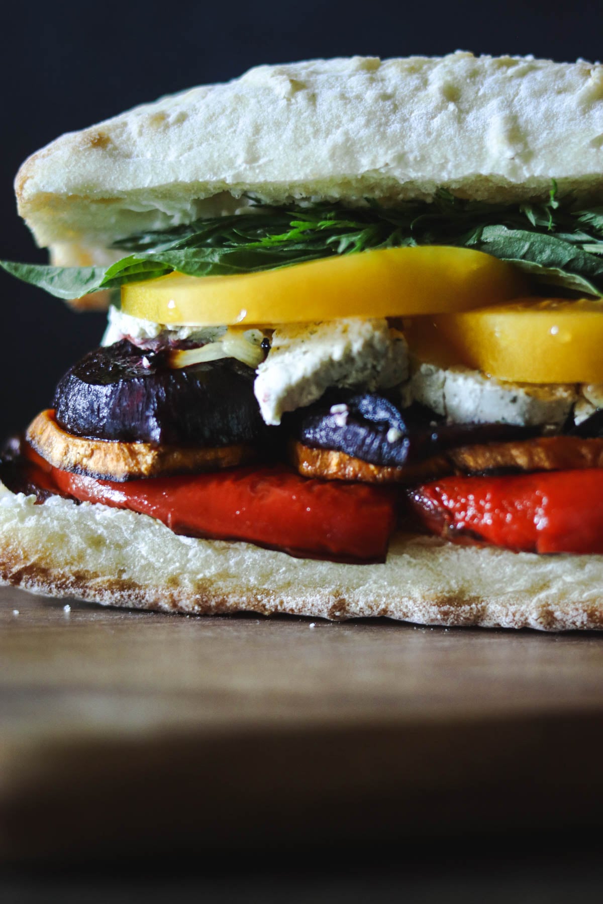 Roasted vegetable sandwich on a wooden board.