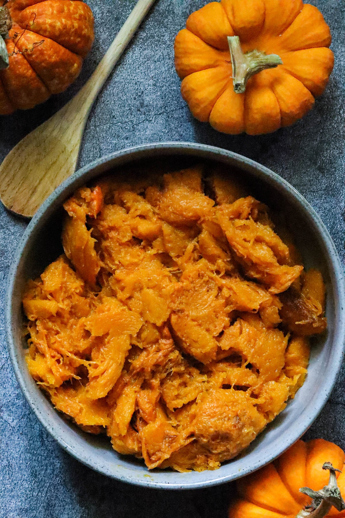 Pumpkin puree in a gray bowl with a wooden spoon.