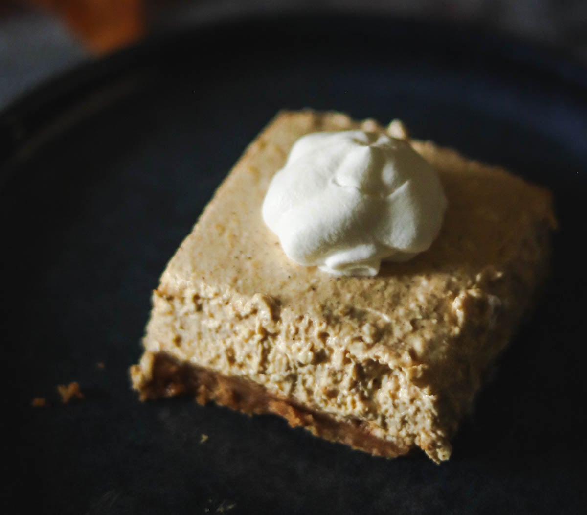 One pumpkin cheesecake bar on a plate.