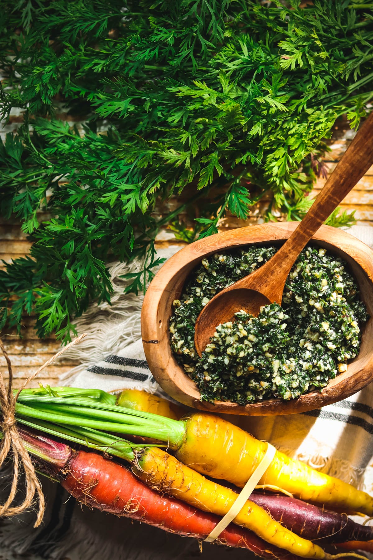 Carrot top pesto next to a bunch of rainbow carrots.