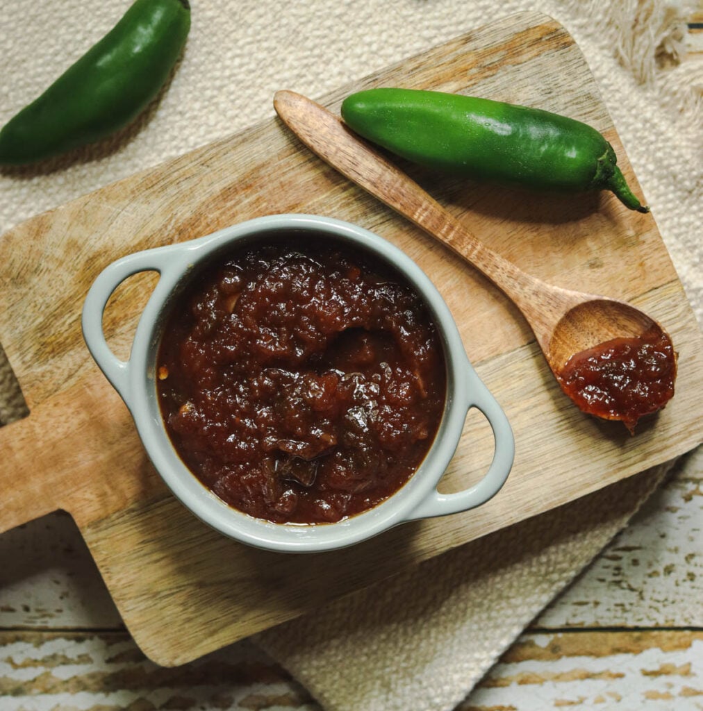 Dish of barbeque sauce with a wooden spoon.