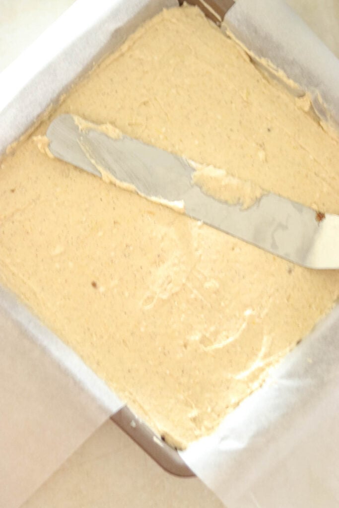 Spreading the cheesecake batter on top of the crust.