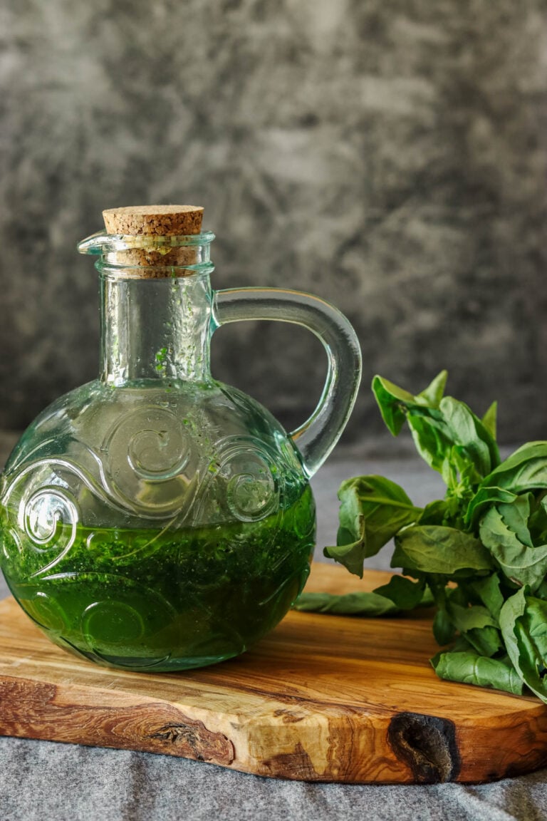Basil and balsamic dressing on a wooden board with fresh basil leaves.