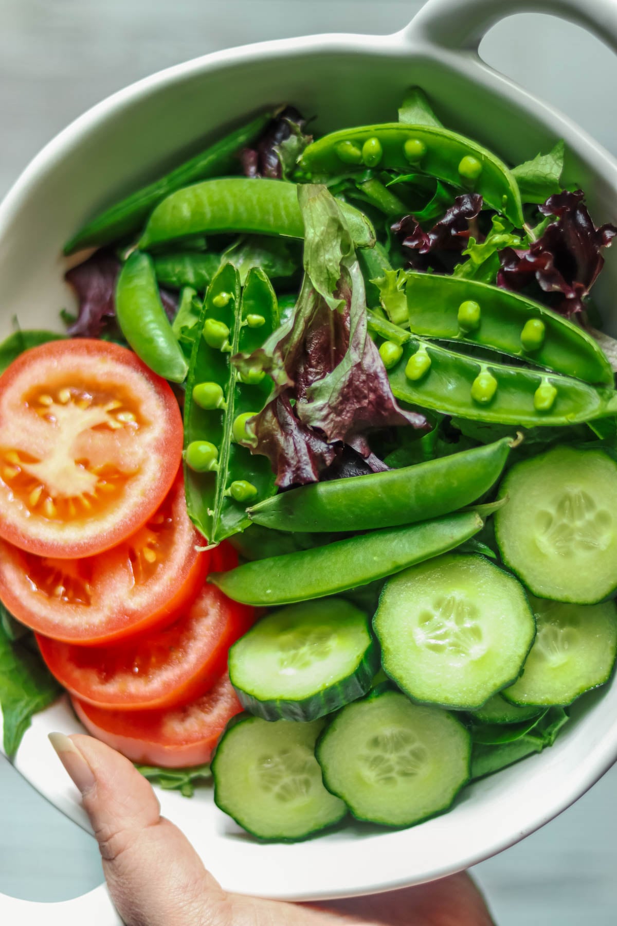 Bowl of salad being held in a hand.