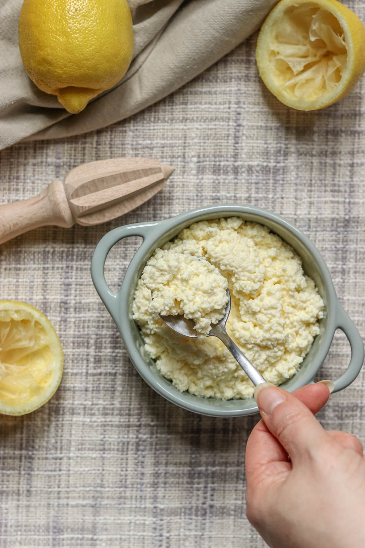 Homemade ricotta in a green dish next to lemons.