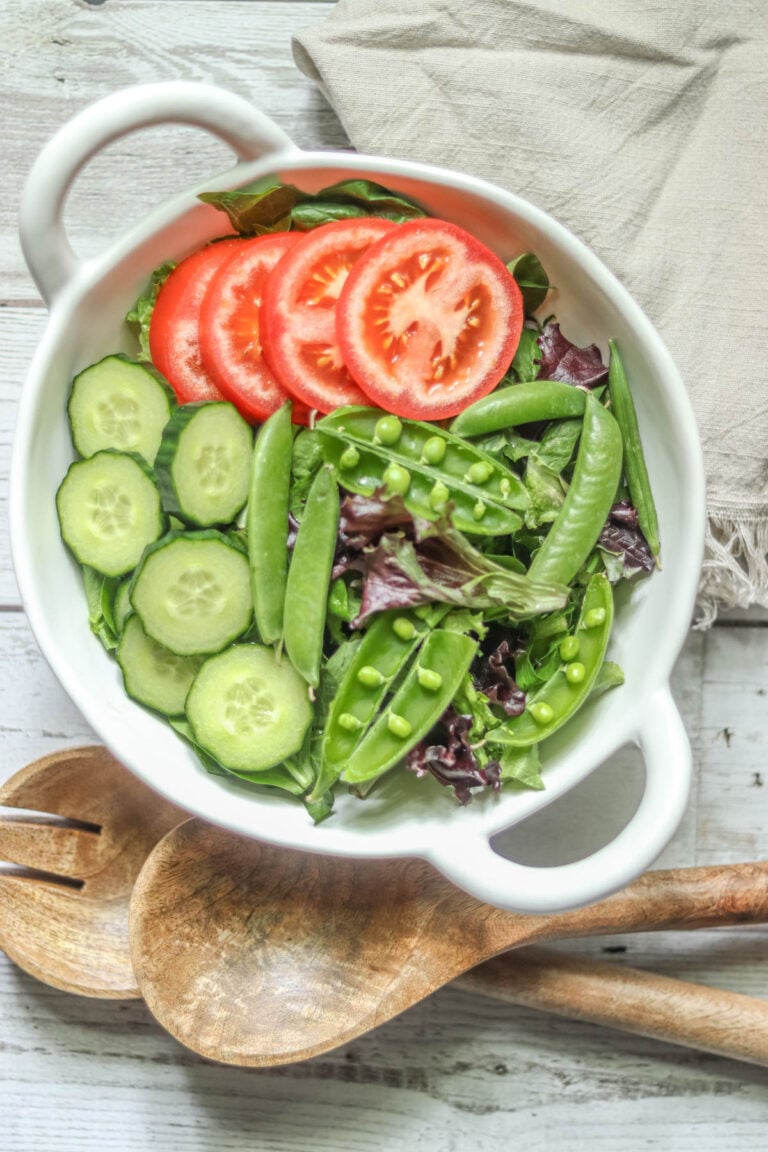 Green salad with wooden spoons and a beige napkin.