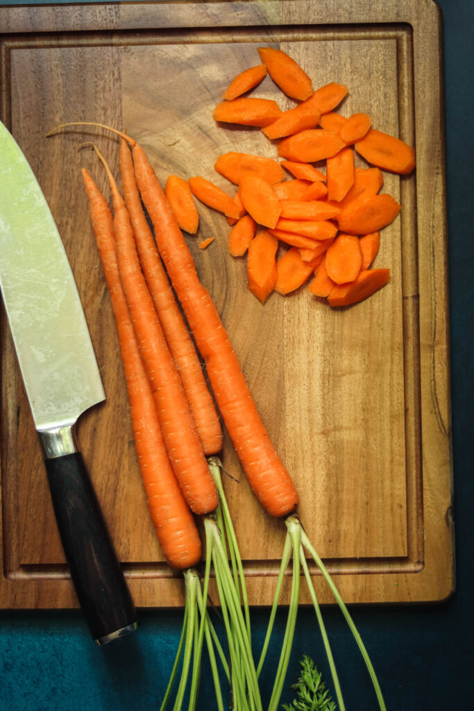 Carrots being sliced on a cutting board.