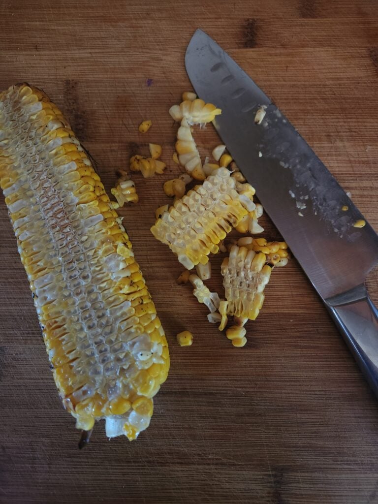 An ear of corn with a knife, and kernels cut from the ear.