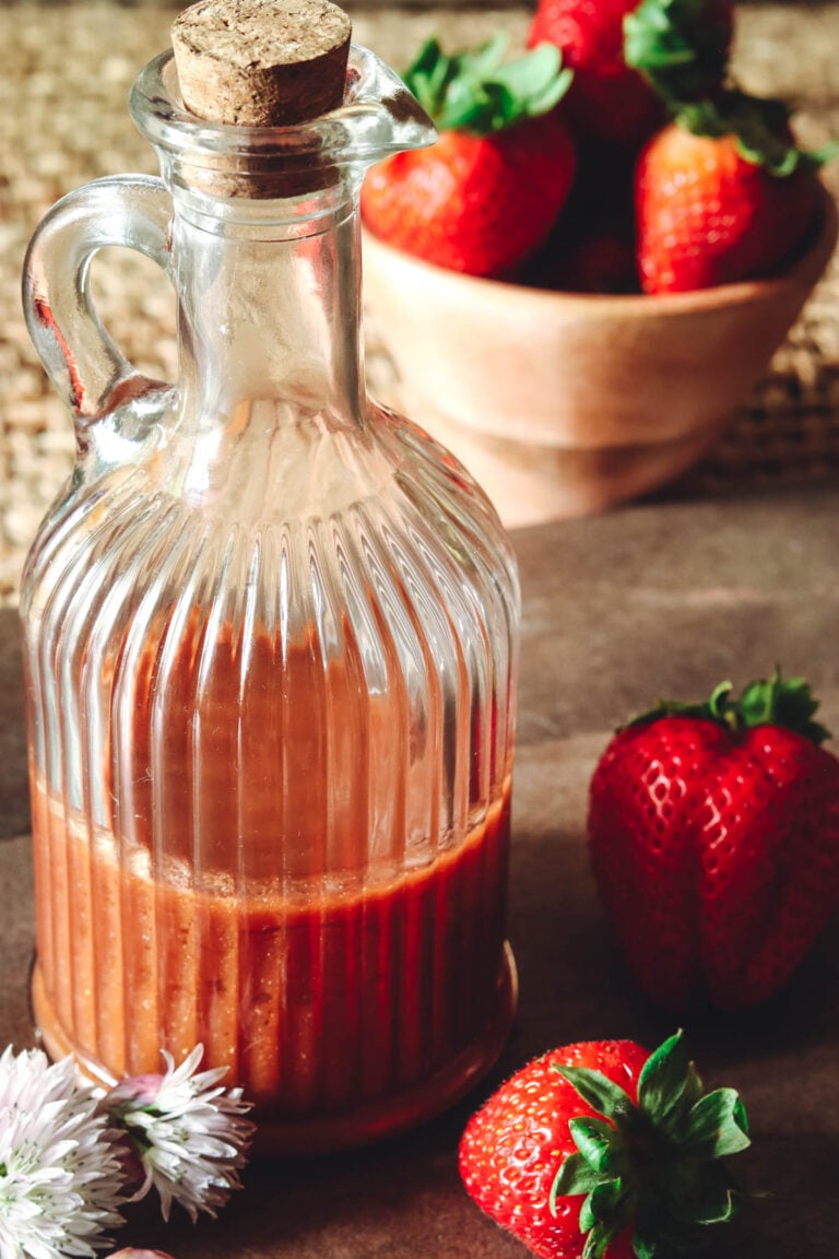 Strawberry vinaigrette with balsamic in a bottle with strawberries next to it.
