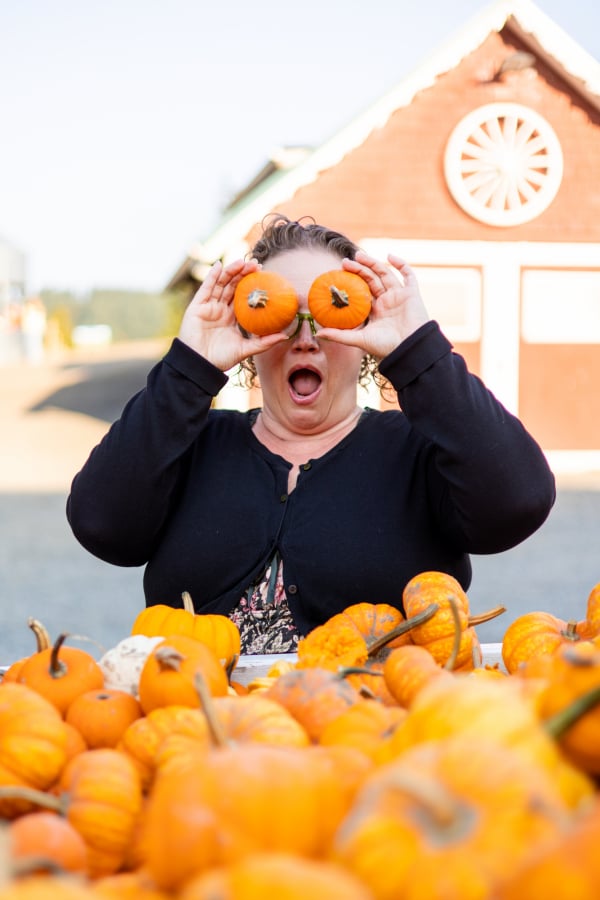 Amy holding mini pumpkins over her eyes.