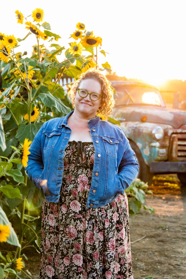 Amy standing next to sunflowers in front of a truck.