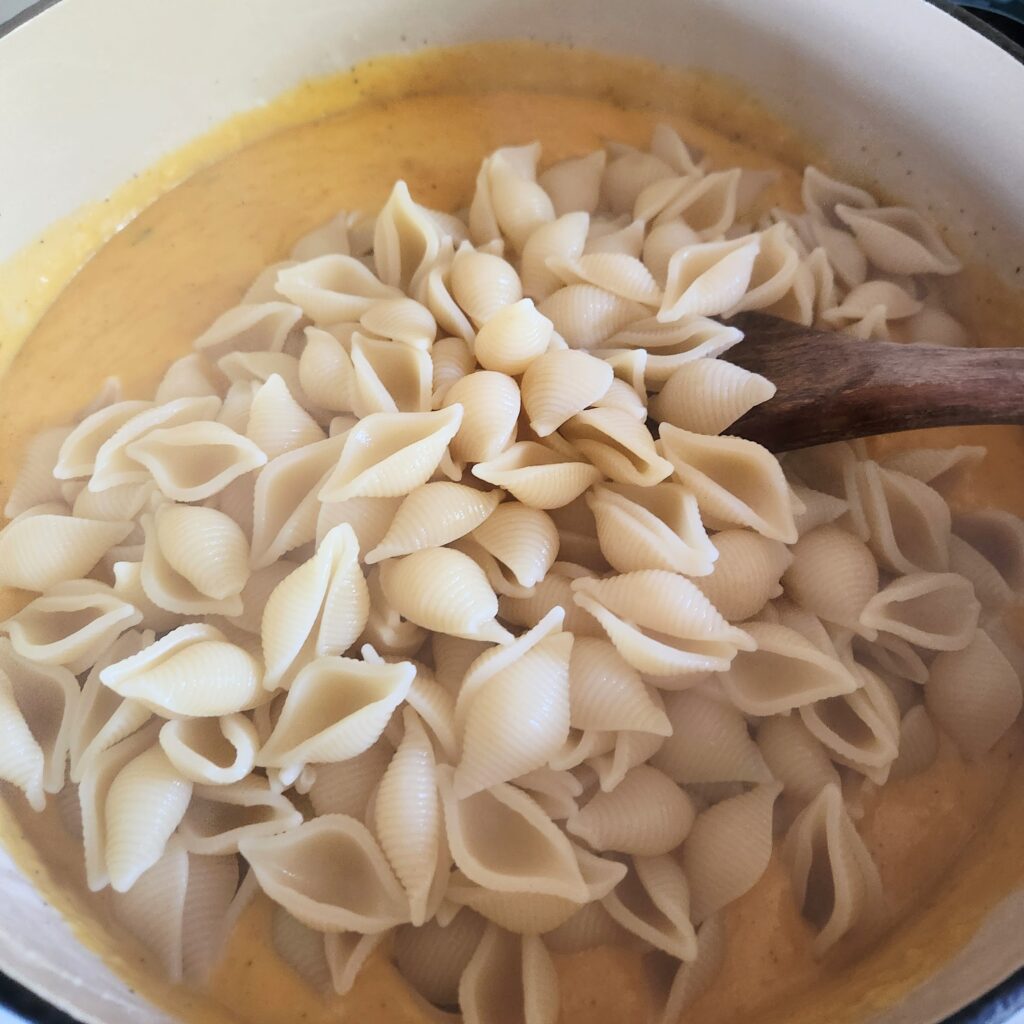 Adding cooked pasta to the sauce.