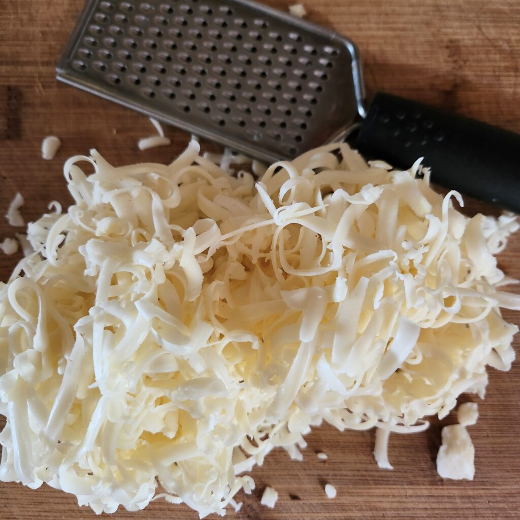 Shredded cheese on a cutting board.