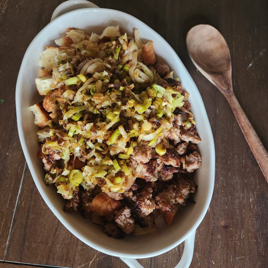 Adding sausage and leeks to the croissant cubes.