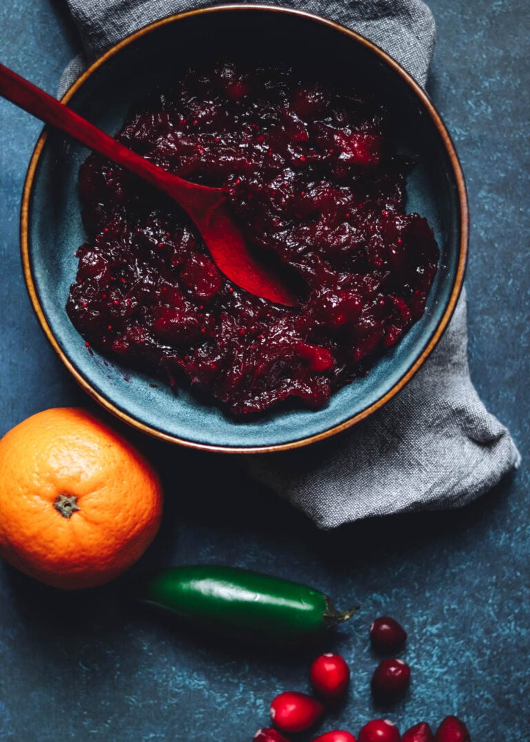 Homemade cranberry sauce with jalapeno in a bowl with a wooden spoon.