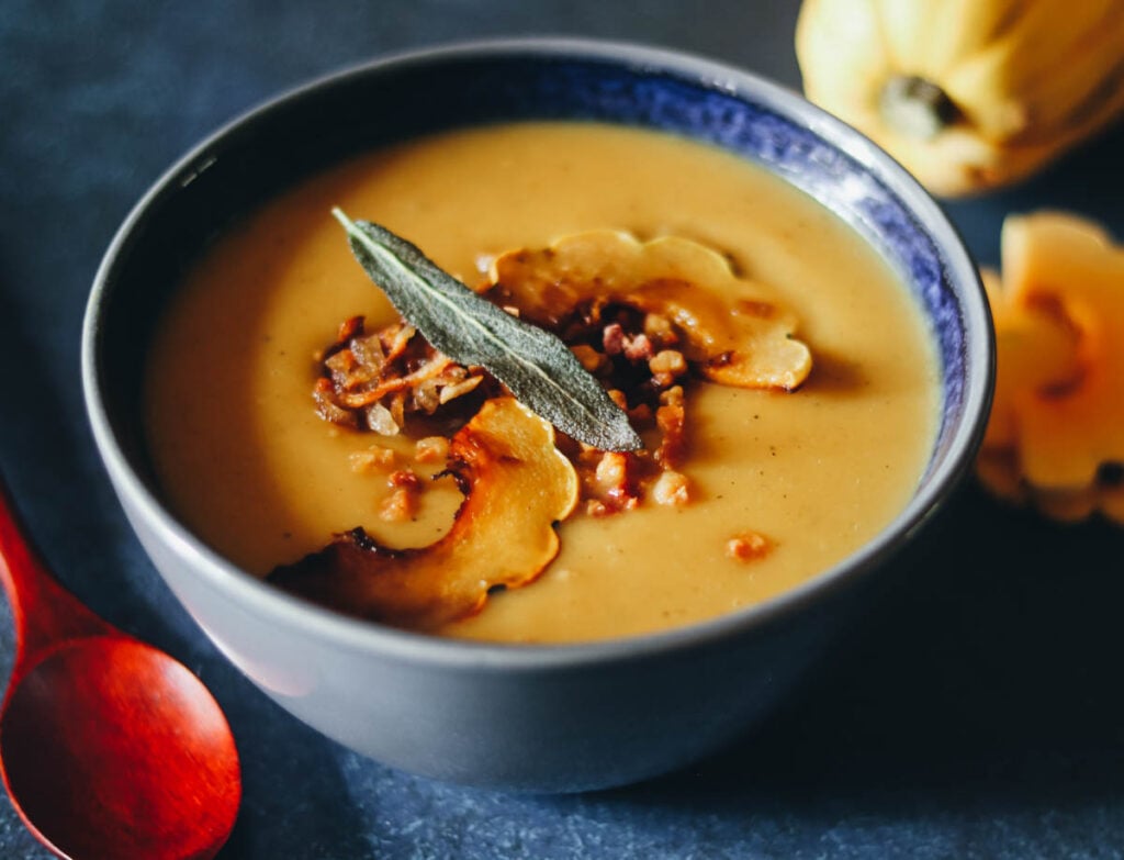 Delicata squash soup in a bowl topped with shallots.