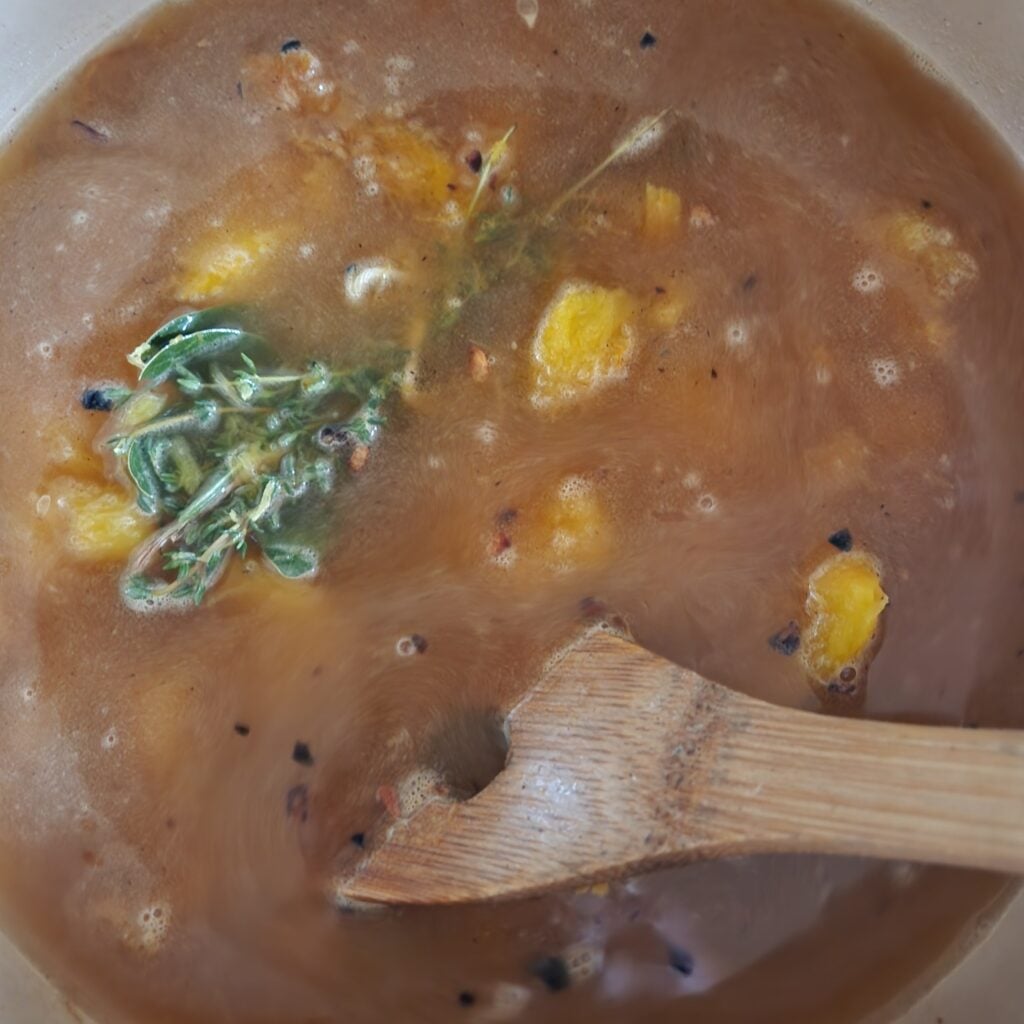Adding stock to the soup.