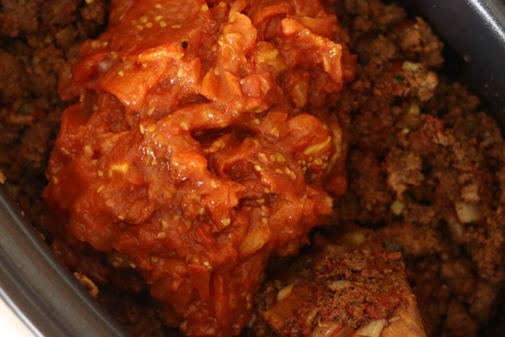 Adding the tomatoes to the slow cooker.