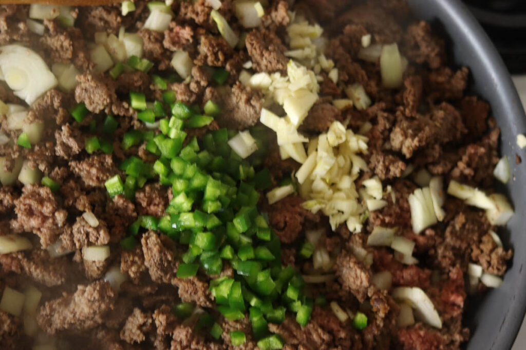 Ground beef, garlic, jalapeno, and onion in browning in a pan.