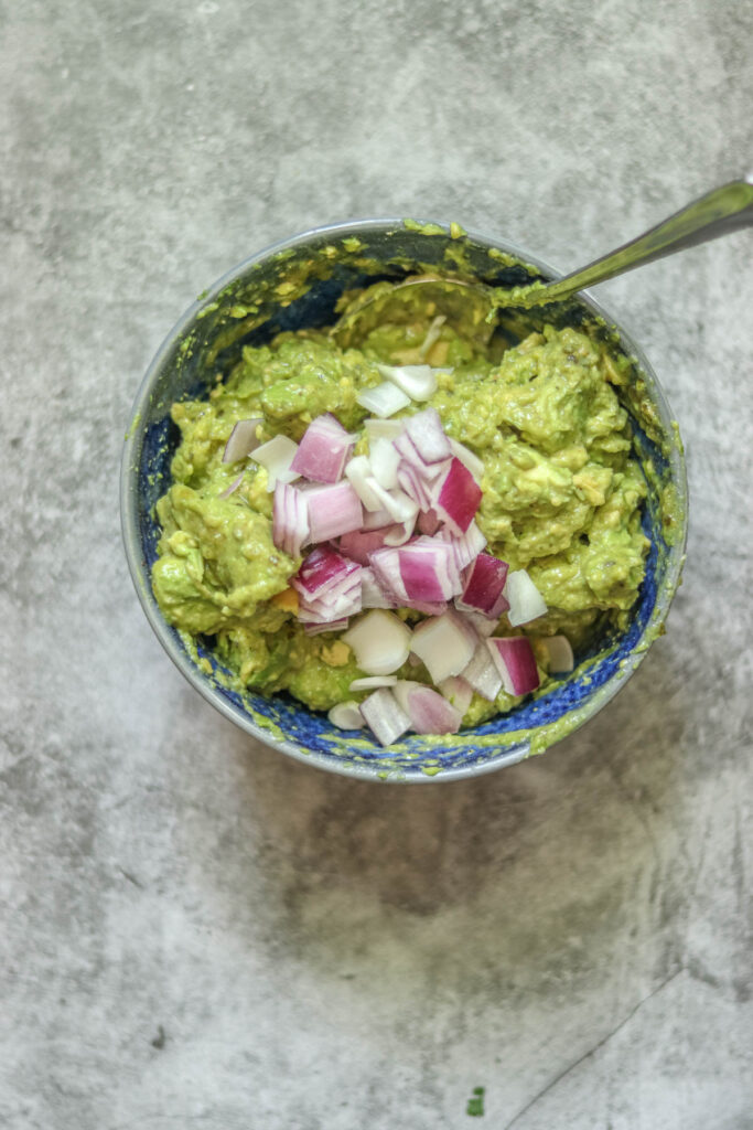 Adding red onion to the guacamole.