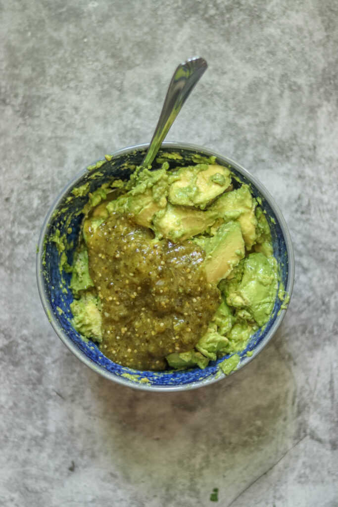 Adding salsa verde to the guacamole.
