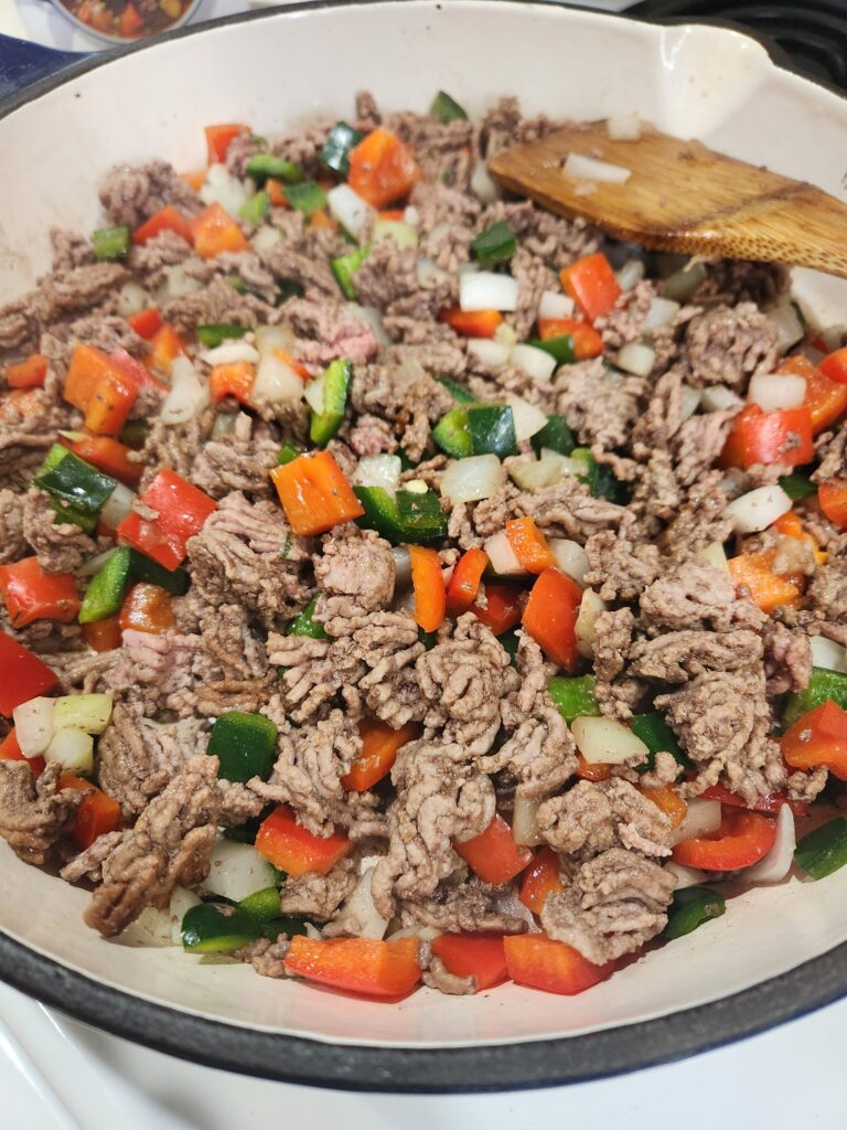 Beef and veggies cooking in a skilet.
