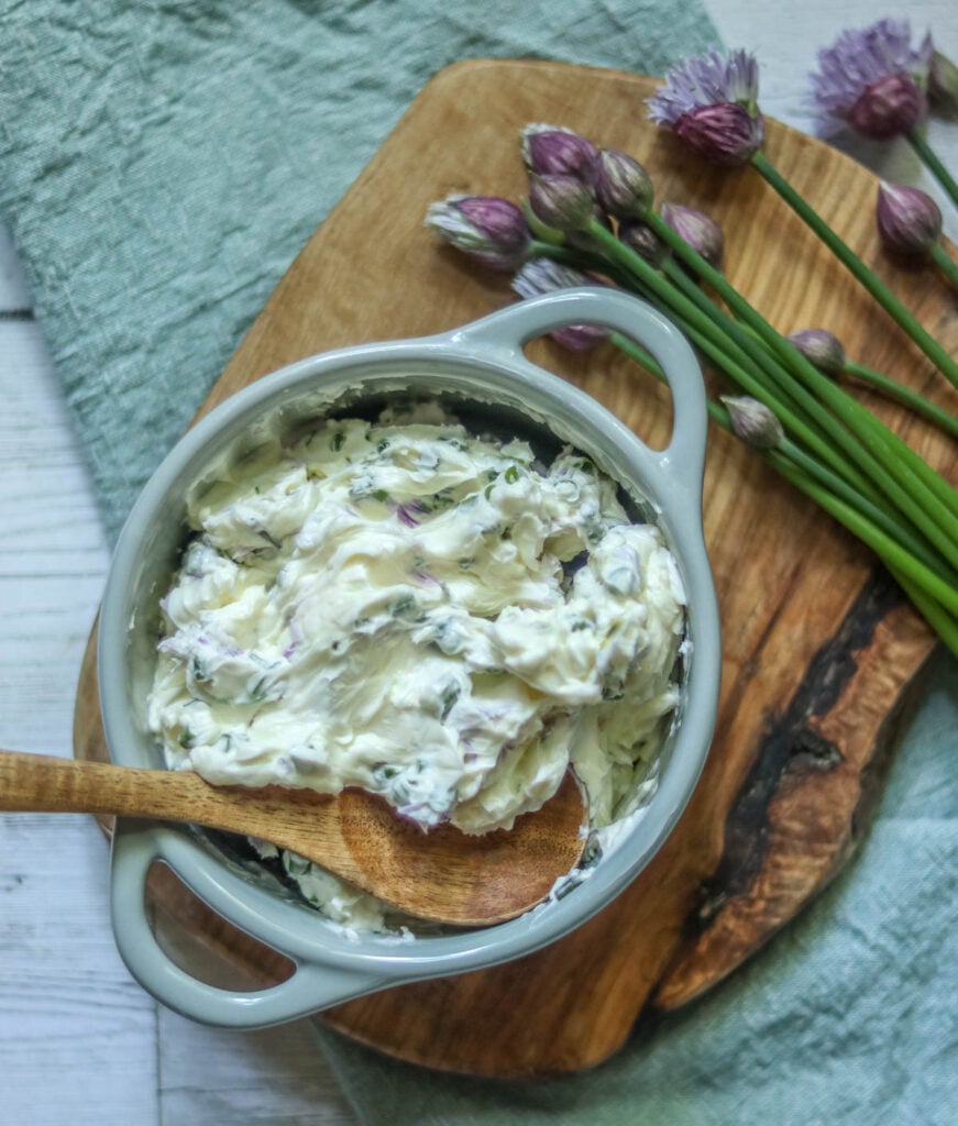 Dish of chive compound butter with a wooden spoon.